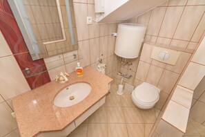 A bathroom with a granite countertop sink, a toilet, and a hand dryer.