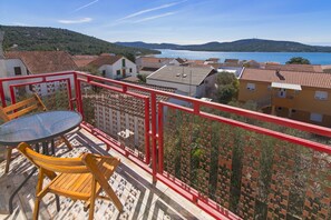 A balcony with a red railing, a round table, and two wooden chairs.