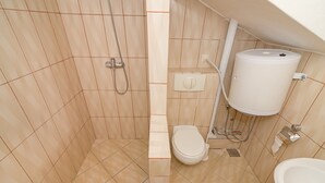 Ett badrum med beige kakel, en toalett, ett handfat och en dusch.