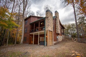 A rustic cabin with a stone chimney, wooden porch, and a view of the surrounding forest. - Cabin getaway in downtown! (Blue Ridge)