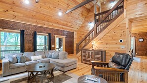 A spacious living room with a wooden staircase, a sofa set, and a dining area.