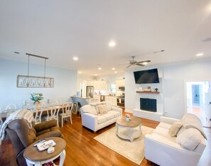 Relax in this open-plan living space with a comfortable sofa set, fireplace, and mounted TV.