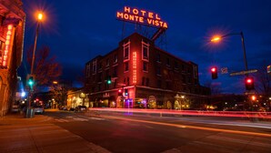 A hotel with a prominent neon sign, a street intersection, and traffic lights.