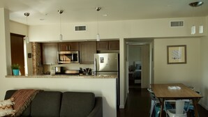 A modern kitchen with stainless steel appliances, a dining area with a wooden table and chairs, and a cozy seating area with a sofa.