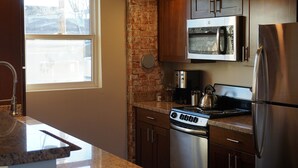 A modern kitchen with granite countertops, stainless steel appliances, and wooden cabinets.