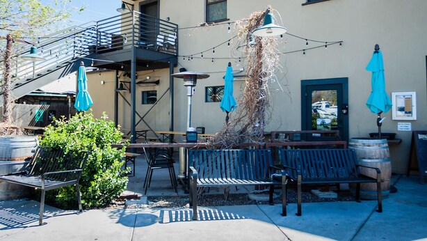 An outdoor seating area with benches and umbrellas, a staircase, and a building with a window and a door.