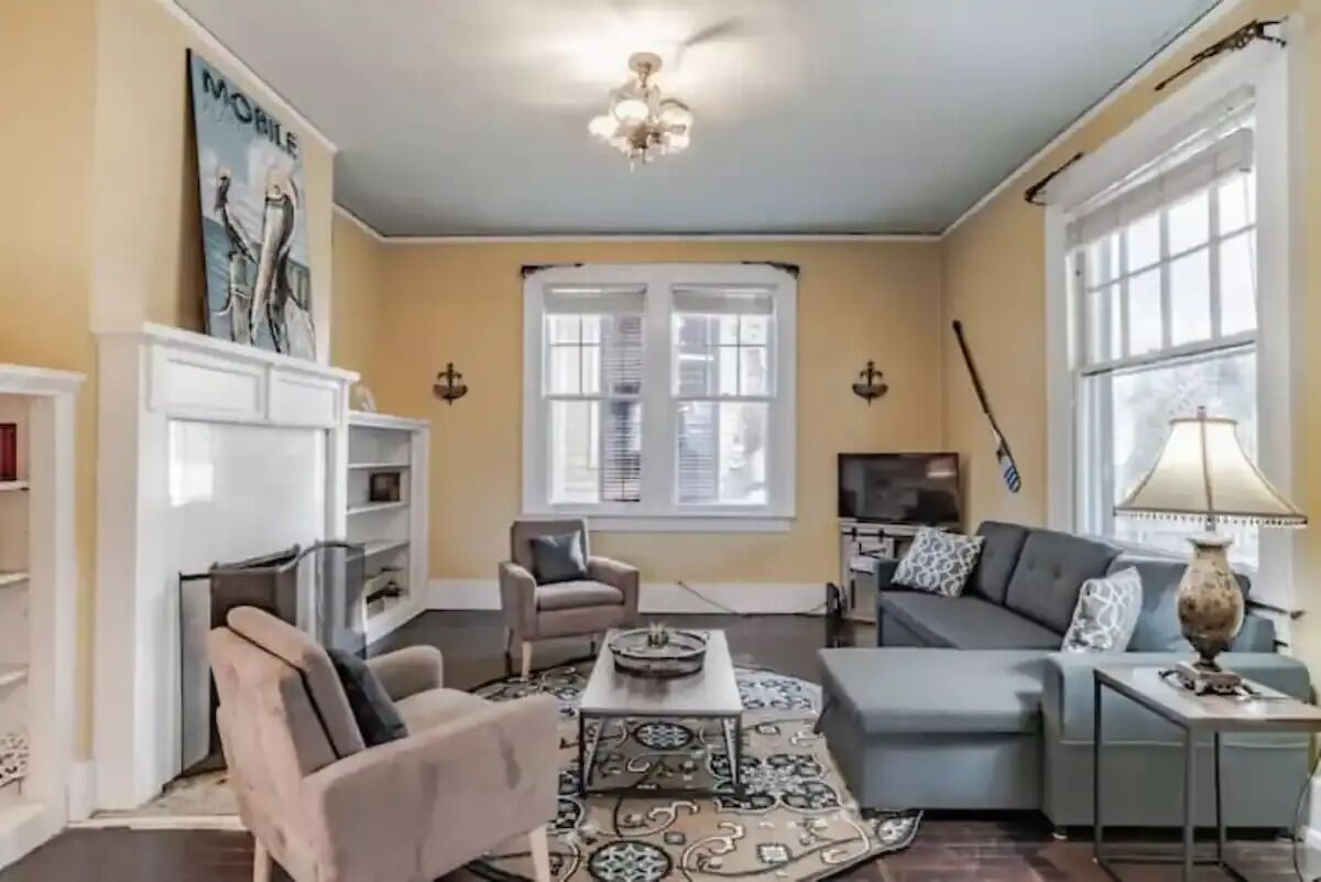 A living room with a sofa, armchairs, a coffee table, and a patterned rug.