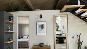 Ein modernes Schlafzimmer im Loft-Stil mit Holzbalkendecke, einem großen Spiegel und Blick zum Essbereich.