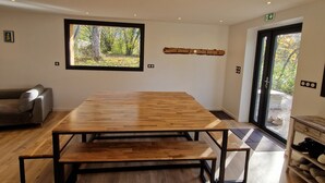 Um quarto amplo com uma grande mesa de madeira, um sofá e uma janela com vista para árvores.