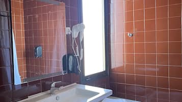 Een badkamer met een witte wastafel, een spiegel, een handdoek en een raam.