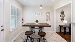 A dining area with a wooden table, two stools, a pendant light, and a small potted plant. - 3B/2Bth Clean, Cozy, Convenient (Fresno)