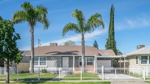 A residential house with a garage, a white picket fence, and palm trees. - 3B/2Bth Clean, Cozy, Convenient (Fresno)