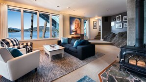 A modern living room with a fireplace, large windows with a view of a bridge and water, and a cozy seating area.