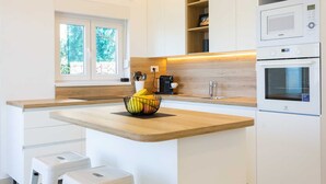 Una cocina moderna con armarios blancos, encimera de madera, cafetera y microondas.