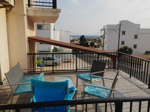 Un balcón con una mesa y sillas, vista a la ciudad y barandilla.