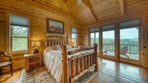 Cozy bedroom with a large bed, scenic views, and a rustic charm.