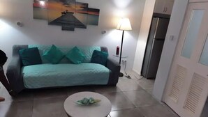A living room with a teal sofa, a small round coffee table, and a lamp.