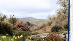 A garden with a stone pathway, a statue, and a view of hills in the background. - 2 bed rural retreat nestled in the heart of Exmoor (Parracombe)