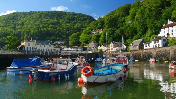 A harbor with boats docked, surrounded by houses and greenery. - 2 bed rural retreat nestled in the heart of Exmoor (Parracombe)