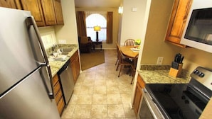 A compact kitchen with a refrigerator, stove, and microwave. There is a dining area with a table and chairs. - 2 bedroom private villa, with pools & hot tubs! (St. George)