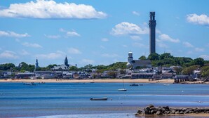 Une ville côtière dotée d’une tour imposante, d’une plage de sable et d’eaux calmes où naviguent des bateaux.