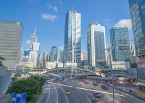 A cityscape with modern skyscrapers, a multi-lane highway, and a pedestrian bridge. - Kings Hotel (Kowloon)