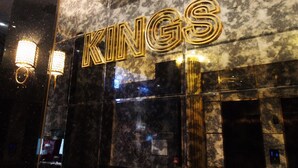 Ein Hotel mit Marmorfassade und leuchtendem 'KINGS'-Schild.