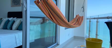 Un balcon avec un hamac, un lit avec des oreillers et une table avec des tasses jaunes.