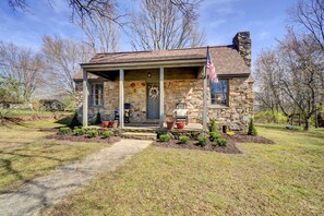 A stone house with a porch, a flag, and a wreath. - Historic Tennessee Vacation Rental on Homestead (Crossville)