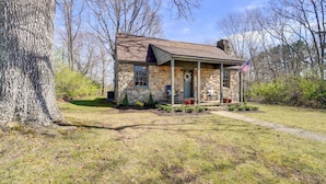 A stone house with a porch, a front door, and a small garden area. - Historic Tennessee Vacation Rental on Homestead (Crossville)