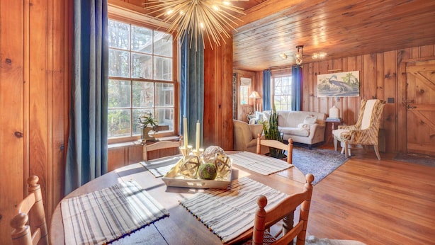 A wooden interior with a dining table set for four, a sofa, and a chair. - Historic Tennessee Vacation Rental on Homestead (Crossville)