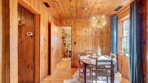 A wooden interior with a dining area, a stone wall, and a ceiling light fixture. - Historic Tennessee Vacation Rental on Homestead (Crossville)