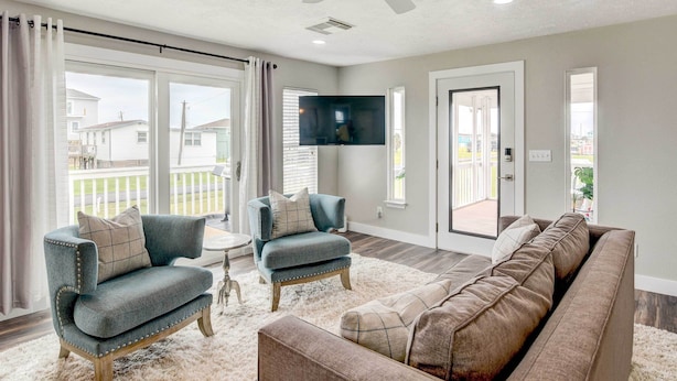 A living room with a sofa, two armchairs, a flat-screen TV, and a ceiling fan. - Walk to Beach & Bay: Galveston Home w/ Pier Access (Galveston)