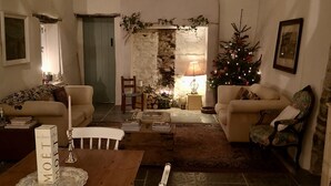 A cozy living room with a fireplace, a Christmas tree, and a dining area with a table and chairs.
