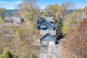 A two-story house with a garage, surrounded by trees and a clear sky. - Blue Anchor Beach Home: Private Beach Access, Large Family Room, Spacious Accommodations (Holland)