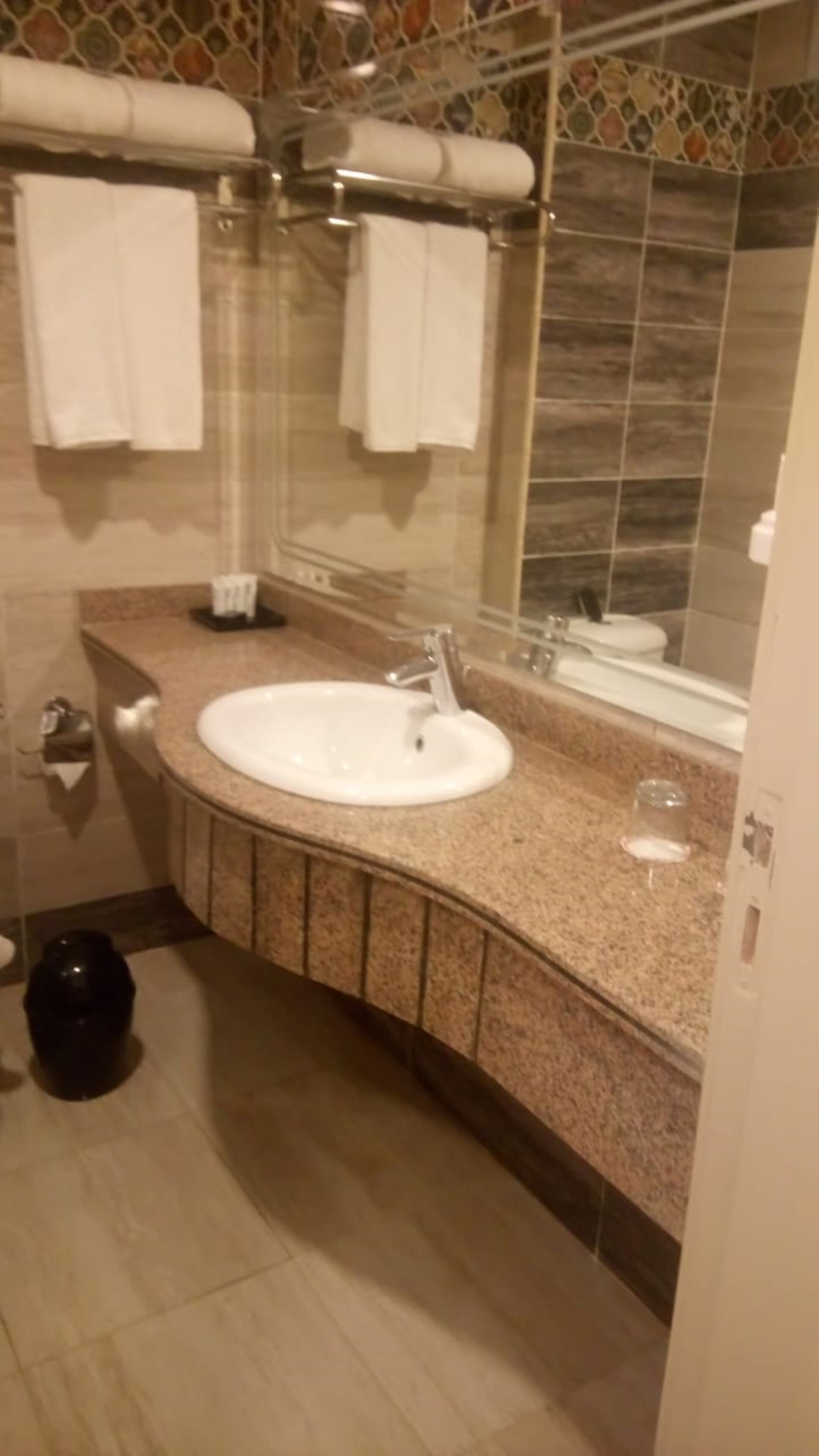 A bathroom with a sink, mirror, and tiled walls.