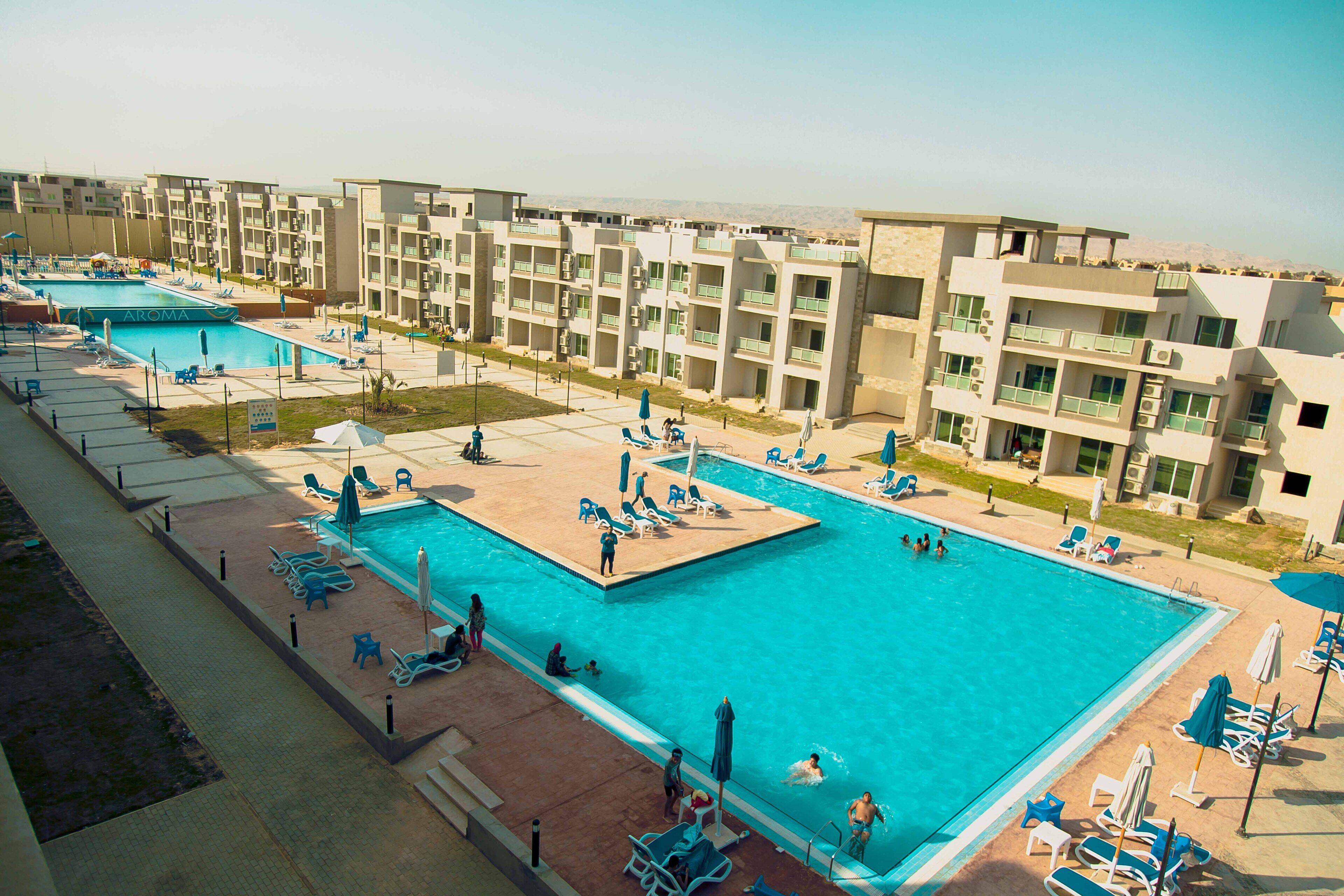 A swimming pool area with multiple pools, sun loungers, and umbrellas.