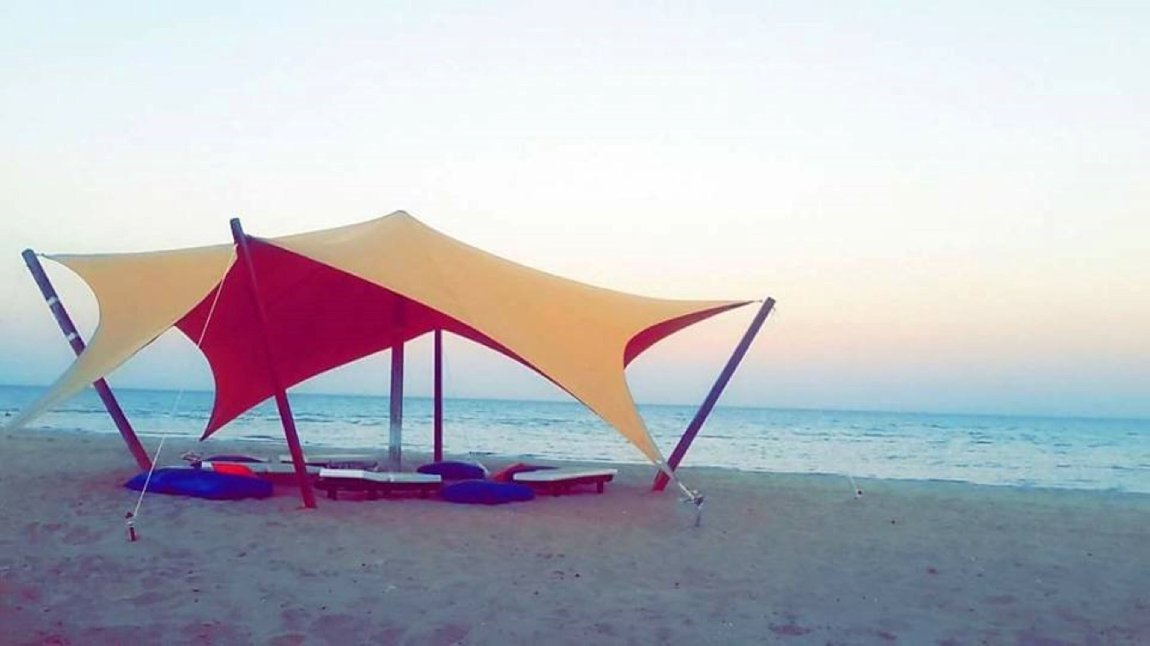Una playa con una estructura tipo sombrilla y sillas de descanso.