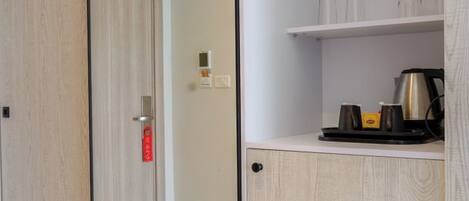 A modern room with a sliding door, a white cabinet with shelves, and a coffee maker.