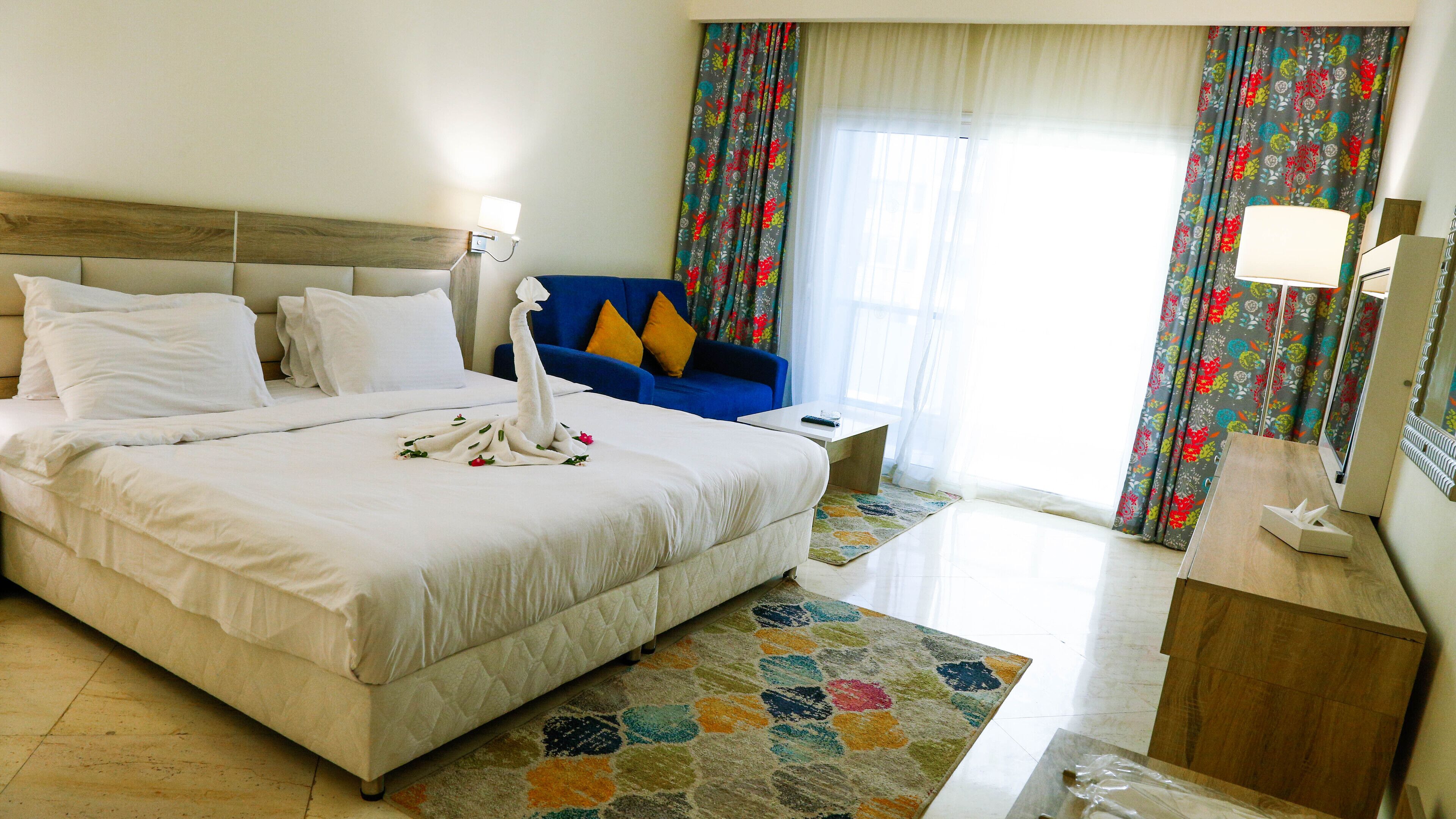 A hotel room with a large bed, a blue sofa, a small table, and a mirror.