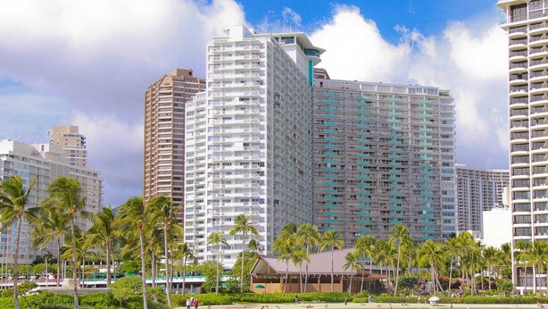 A beachfront hotel with multiple high-rise buildings, palm trees, and a sandy beach.