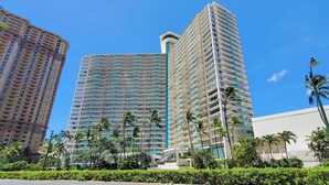 A high-rise hotel with multiple floors, a prominent entrance, and a clear blue sky.