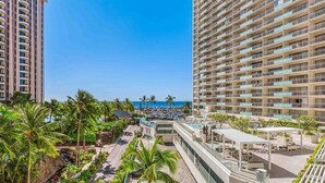 A high-rise hotel with a rooftop pool, palm trees, and a view of the beach.