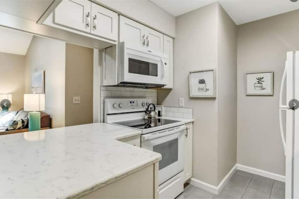 A kitchen with white cabinets, a microwave, an oven, and a refrigerator.