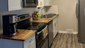 Eine moderne Küche mit weißen Schränken, Edelstahlgeräten und einer Holz Arbeitsplatte.