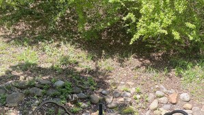 Ein Metalltisch mit vier Stühlen, einer Weinflasche und zwei Gläsern auf einer Betonplatte.