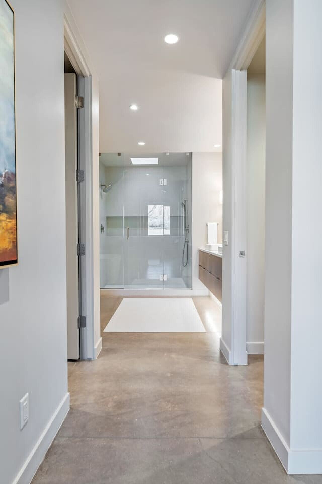 A modern bathroom with a glass shower enclosure, a white vanity, and a large mirror.