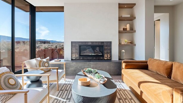 Ein modernes Wohnzimmer mit Kamin, großen Fenstern und Blick auf die Wüstenlandschaft.