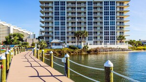 Un hôtel à plusieurs étages doté de balcons, offrant une vue sur le front de mer et comprenant une promenade en bois qui mène à l’eau.