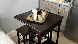 A compact kitchen with a countertop, sink, and a refrigerator. There is a small dining table with a tray of items on it. - Luxurious little home! (Hialeah)